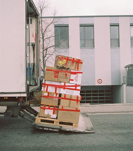 A crate of packages and boxes wrapped on the back of a lorry.