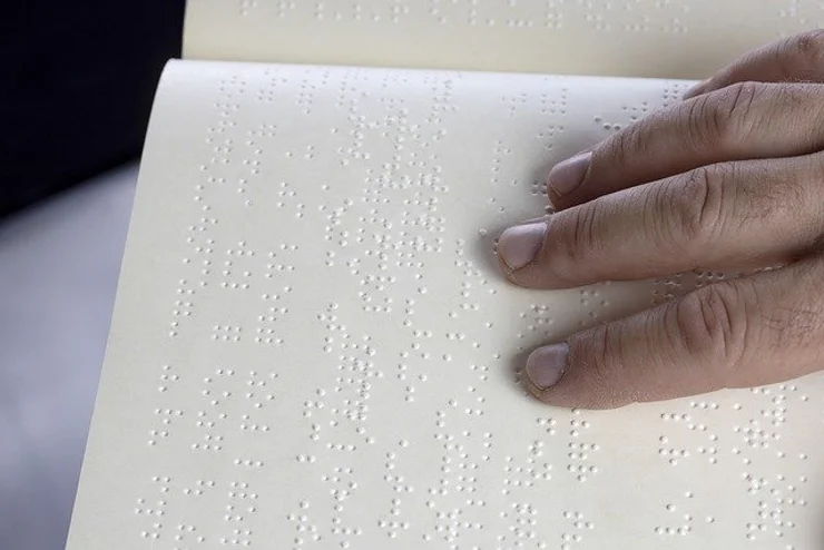 An image of a hand reading a book in Braille.