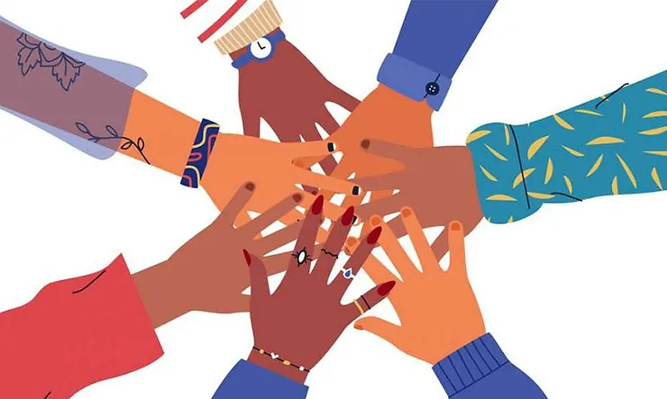 A group of diverse hands touching to show inclusion and diversity.